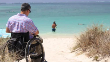 Diportista in carrozzina sulla spiaggia davanti al mare